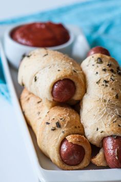 two hot dogs wrapped in bread with ketchup on the side