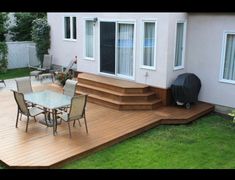 a backyard deck with chairs, table and grill