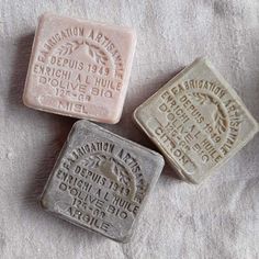 three soap bars sitting on top of a white towel next to each other, one with an inscription