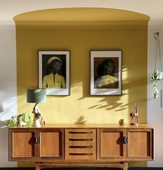 a room with two pictures on the wall and a sideboard in front of it