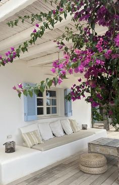 a white couch sitting on top of a wooden floor next to a window covered in purple flowers