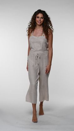 Effortlessly chic, this taupe-colored cover-up complements any beach ensemble, offering a versatile and neutral layer for your seaside adventures. This jumpsuit features a cropped, wide-leg design, with adjustable shoulder straps and a drawstring waist for a customizable fit. The back showcases a cross-strap detail, adding a touch of elegance to the relaxed fit, making it both functional and fashionable for summer days. [split] Details Jumpsuit cover up Cropped length Drawstring waistband Pocket Linen Jumpsuit For The Beach, Solid Beach Overalls, Chic Beach Bottoms With Adjustable Straps, Solid Overalls For The Beach, Chic Bottoms With Adjustable Straps For Beach, Summer Neutral-colored Jumpsuits And Rompers With Pockets, Neutral Summer Jumpsuits And Rompers With Pockets, Neutral Summer Casual Jumpsuits And Rompers, Summer Neutral Jumpsuits And Rompers With Pockets