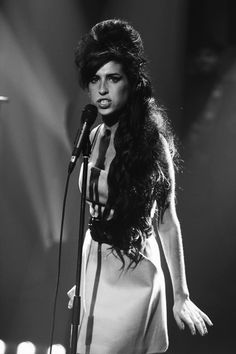 a woman with long hair standing in front of a microphone