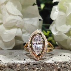 a yellow gold ring with a pear shaped diamond in the center surrounded by white flowers