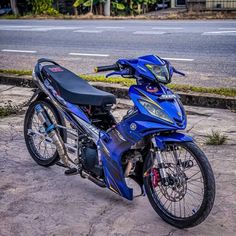 a blue motorcycle parked on the side of a road next to a street with cars