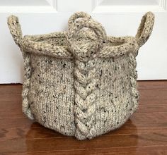 a knitted basket sitting on the floor in front of a door with wood floors