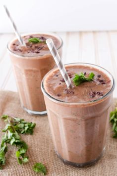 two glasses filled with chocolate smoothie and garnished with fresh mint sprigs