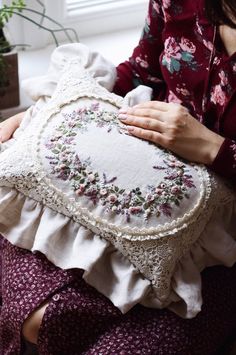 a woman sitting on the floor holding a pillow