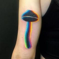 a colorful mushroom tattoo on the left arm and shoulder, with an inverted rainbow design