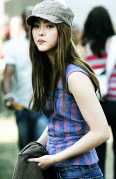 a young woman with long hair wearing a hat and holding a brown bag in her hand