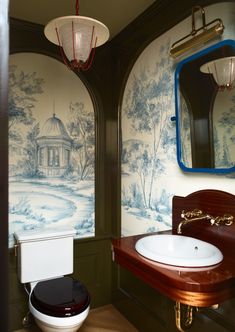 a toilet and sink in a small room with wallpapers on the walls behind it