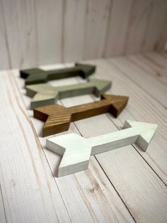 four wooden arrows arranged in the shape of an arrow on a white wood floor with planks