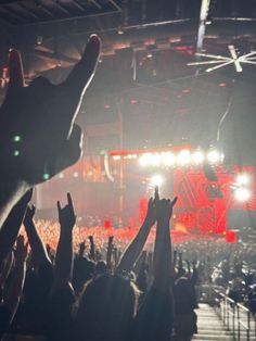 a crowd of people at a concert with their hands in the air and lights on