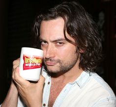 a man with long hair holding a coffee cup