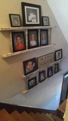 some pictures are hanging on the wall and there is a shelf that has several frames above it