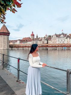 a woman standing on a railing looking at the water