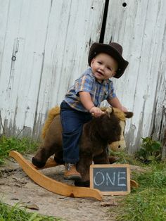 a young boy riding on the back of a toy horse next to a chalkboard