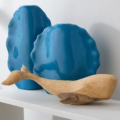 two blue vases sitting on top of a white shelf next to a wooden object