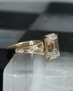 an antique diamond ring on top of a marble block with diamonds in the band and sidestones