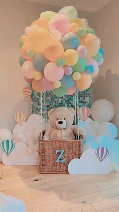 a teddy bear sitting in a basket with balloons