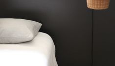 a lamp that is next to a bed with white sheets and pillows on top of it