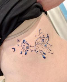 a woman with a tattoo on her stomach has a blue flower and stars design on her back