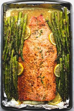 baked salmon and asparagus in a pan with lemons, parsley and seasoning