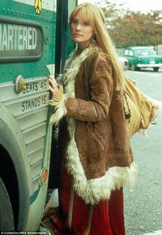 a woman standing in front of a bus with her hand on the back of it