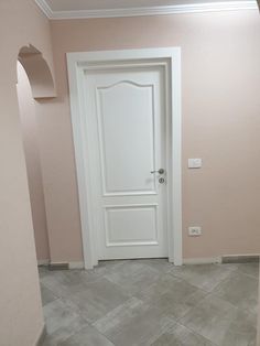 an empty room with a white door and pink walls