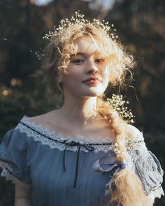 a woman with blonde hair wearing a blue dress and flowers in her hair, looking to the side