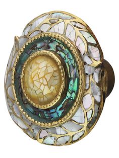 an ornate brass and mother of pearl cabinet door knob with decorative glass inlays