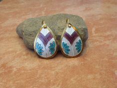 "These vintage 1970s Laurel Burch cloisonné enamel pierced earrings feature Basket of Flowers, and likely a Japanese Kamon Family Crest, in sterling silver 24k gold wash. The enamel colors are Chalk White, Amethyst, Turquoise and Light Rose. Enamels bake at various temperatures, many colors require multiple layers, and fired multiple times. For unknown reasons, light rose/pink and red colored enamels are extremely fragile. Artisans also applied enamel to the backsides to strengthen the bond. Vin Bohemian Gold Enamel Earrings, Gold Bohemian Jewelry With Inlay, Bohemian Gold Jewelry With Inlay, Japanese Kamon, Flowers Japanese, Cloisonne Earrings, Basket Of Flowers, Light Rose, Laurel Burch