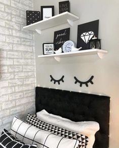 a black and white bedroom with two shelves above the headboard that have eyes drawn on them