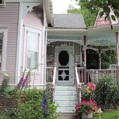 a pink house with lots of flowers in the front yard and stairs leading up to it