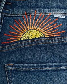 the back pocket of a pair of jeans with embroidered sunbursts on it