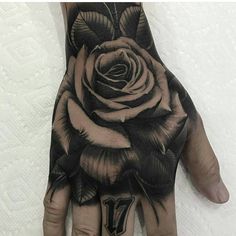 a black and white rose tattoo on the palm of a person's left hand