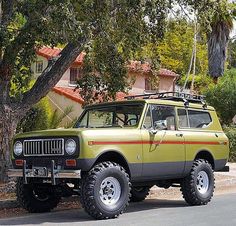 an old yellow jeep is parked on the side of the road in front of some trees