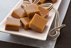 several pieces of caramel fudge on a white plate tied with brown twine