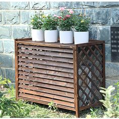 three potted plants sitting on top of a wooden planter in front of a brick wall