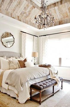 a bedroom with a large bed and a chandelier hanging from it's ceiling