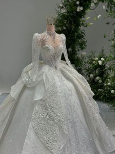 a white wedding dress on display in front of flowers