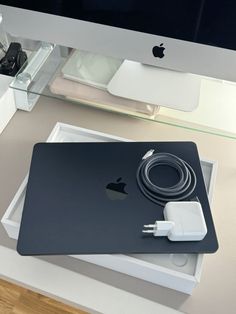 an apple computer is sitting on top of a desk with a charger plugged into it