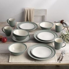 a table set with plates, cups and utensils on top of a wooden table