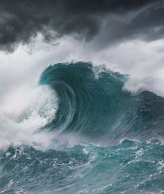 a boat is in the middle of a large ocean wave with dark clouds above it