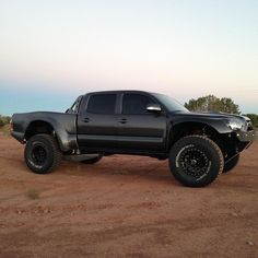 a black truck parked on top of a dirt field