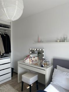 a bedroom with a bed, dressing table and mirror on it's side in front of a white wall