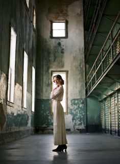 a woman is standing in an old jail cell building with her hands on her chest