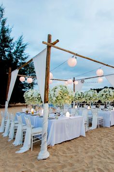 an outdoor wedding set up on the beach with white linens and flower centerpieces