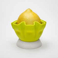 an orange sitting in a yellow bowl on top of a white surface with the lid open