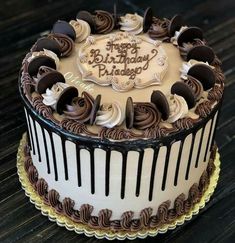 a birthday cake with chocolate icing and frosting on the top is sitting on a table